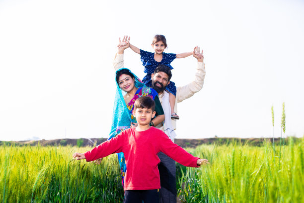 幸福的年轻印度农民家庭站在麦田，父母带着孩子在户外，农村印度的概念。本空间图片下载