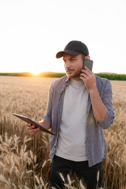 留着胡子的农民拿着手机和数码平板电脑图片下载