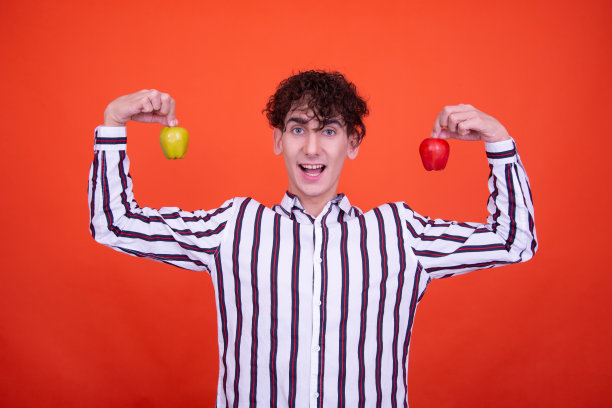 年轻有吸引力的情绪化的家伙在工作室里摆姿势，背景是橙色的。图片下载