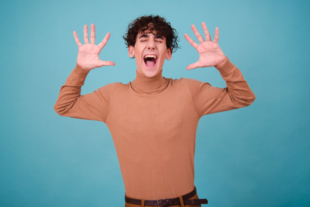 情绪化的家伙在蓝色背景的工作室里摆姿势，既惊讶，又高兴，又悲伤。图片下载
