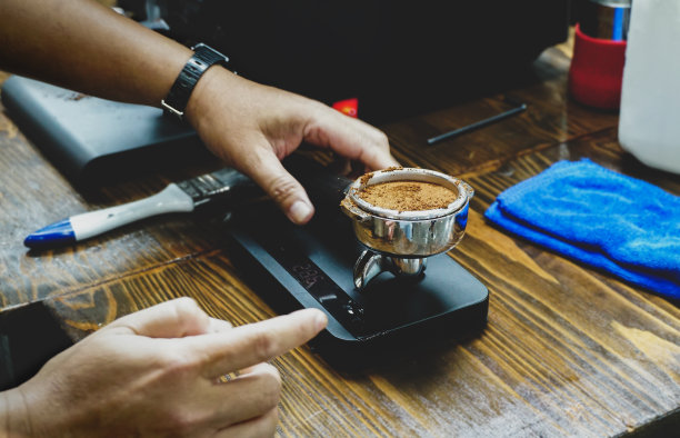 咖啡师拿着木桌上的称重机和磨碎的咖啡过滤机来煮咖啡。咖啡准备服务理念。图片下载