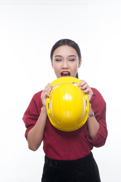 美丽的工程女人拿着红色衬衫和白色背景的黄色头盔。图片下载