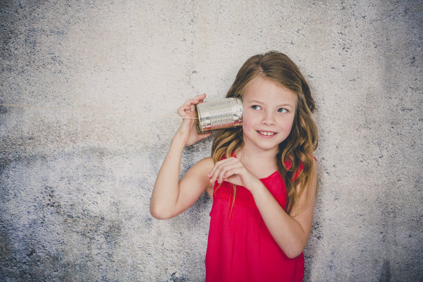 金发碧眼，漂亮的女孩正在用一个罐头做的有线电话打电话图片下载