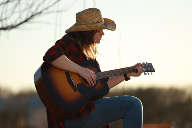 牛仔女郎在日落时弹吉他图片下载