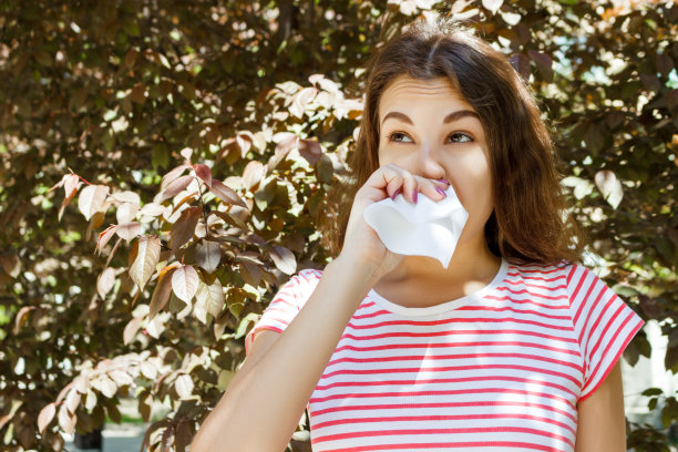 小女孩在擤鼻涕。秋天公园里有过敏的小女孩图片下载