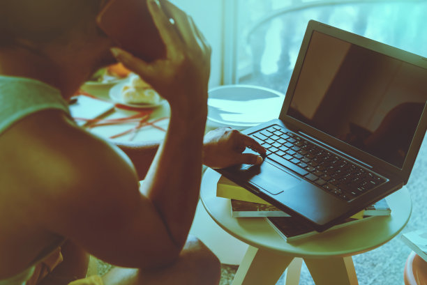 一个人坐在沙发上工作。手里拿着手机，手里拿着笔记本图片下载