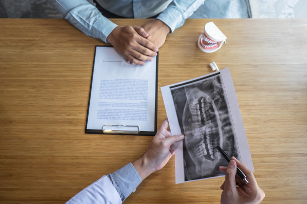 专业牙医出示颌骨和牙齿的x光照片，并在会诊期间与患者讨论治疗问题，并在报告上写下病史清单图片下载