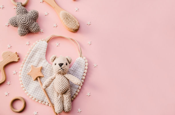 围嘴和木制玩具。一套婴儿用品和配件的女孩在粉彩粉红色的背景。婴儿洗澡的概念。时尚的新生儿。平铺，俯视图图片下载