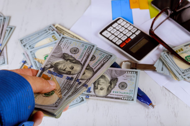 商人以股票市场或金融投资和交易的概念支付美元和使用计算器。图片下载