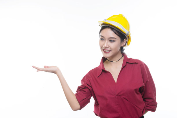 穿着红色衬衫戴着黄色安全帽的工程女工在工作室灯光下指指点点，职业理念，施工准备，快乐工作者图片下载