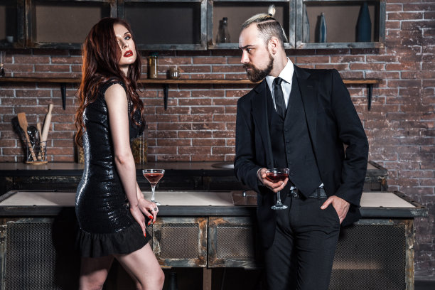 穿着得体的夫妇住在阁楼公寓里。厨房。一对夫妇端着葡萄酒杯对着镜头摆姿势。图片下载