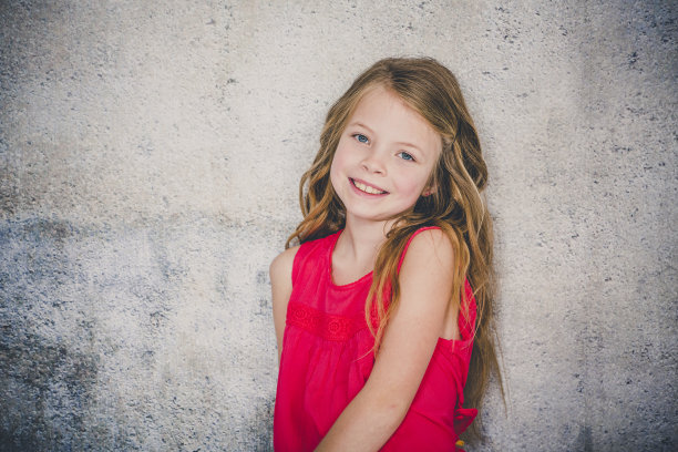 穿着红衬衫的漂亮女孩在混凝土背景前摆姿势并指指点点图片下载