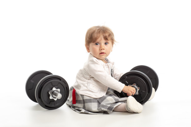 在白色背景的摄影棚里，小女孩在玩健身器材。健身养生理念图片下载