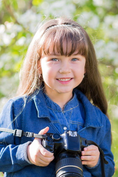 一个漂亮的小女孩手里拿着照相机。图片下载