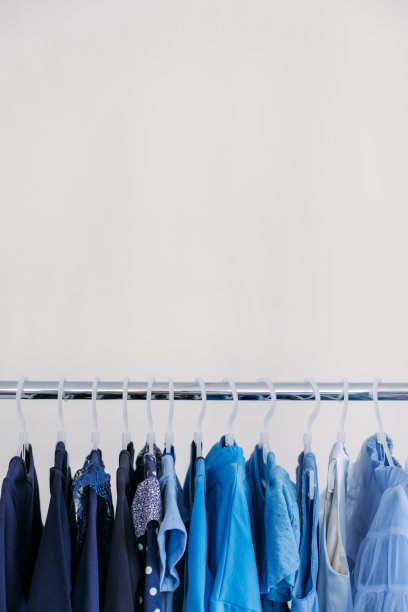 快时尚，可持续时尚，极简衣橱。各种女性蓝色服装挂在白色背景与复制空间。时尚极简风格横幅图片下载