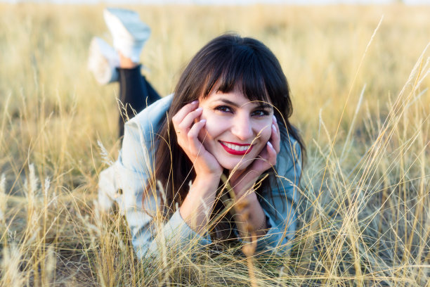 开朗的黑发女孩躺在田野的草地上图片下载
