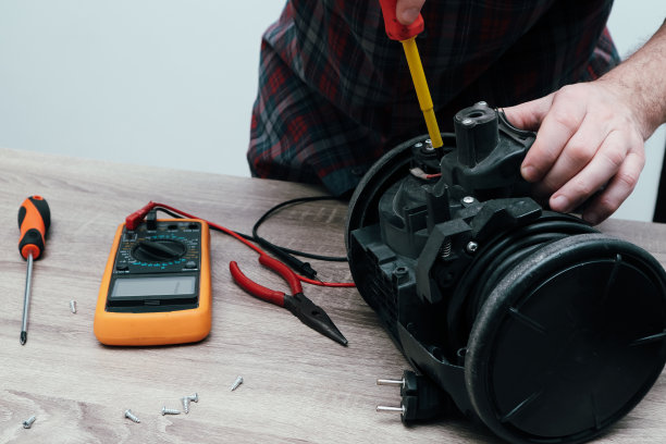 真空吸尘器维修。小生意。专业技术人员正在他的办公室里修理现代吸尘器。图片下载