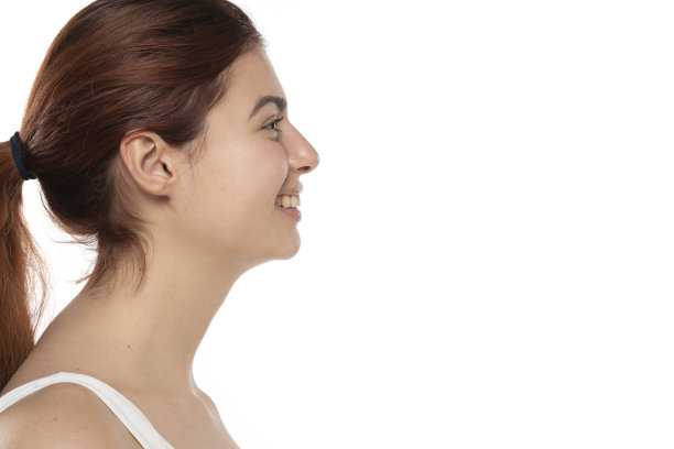 一个年轻的面带微笑的红发女人，没有化妆，长发在白色的工作室背景图片下载