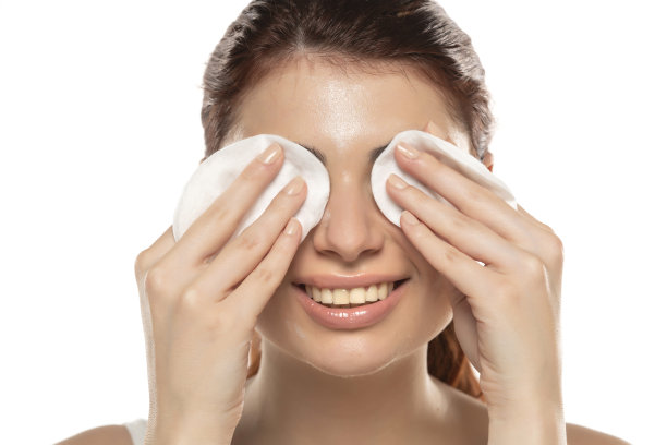 美丽的红发微笑的女人在白色的背景上用棉签洗脸图片下载