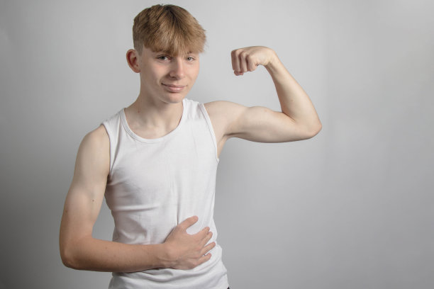 十几岁的男孩在弯曲他的二头肌图片下载