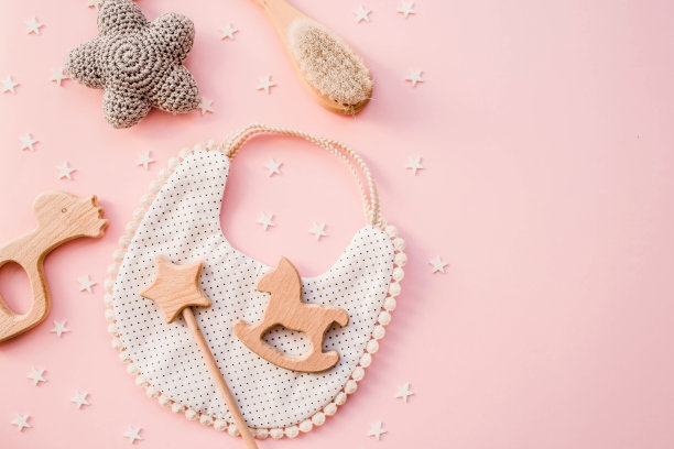 围嘴和木制玩具。一套婴儿的东西和配件的女孩粉彩粉红色的背景。婴儿送礼会的概念。时尚的新生儿。平铺，俯视图图片下载