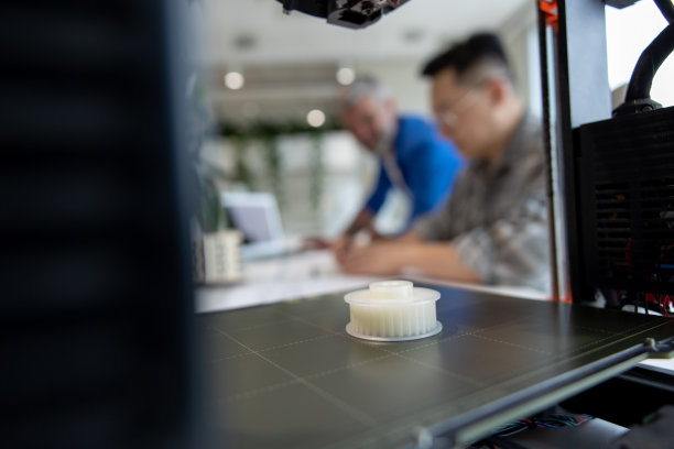 两位建筑师在办公室里使用3D打印机，投影房子，绘制蓝图。图片下载