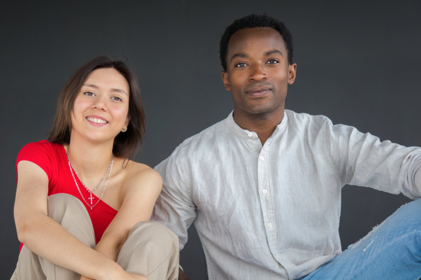 年轻的男女朋友坐在演播室里一起微笑图片下载