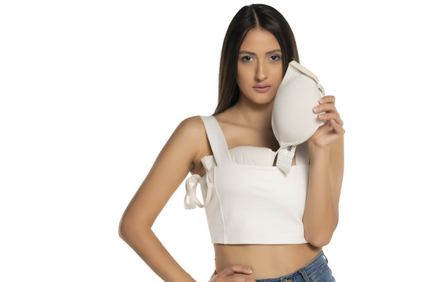 一个年轻漂亮的女人从上衣里抽出她的大胸罩图片下载