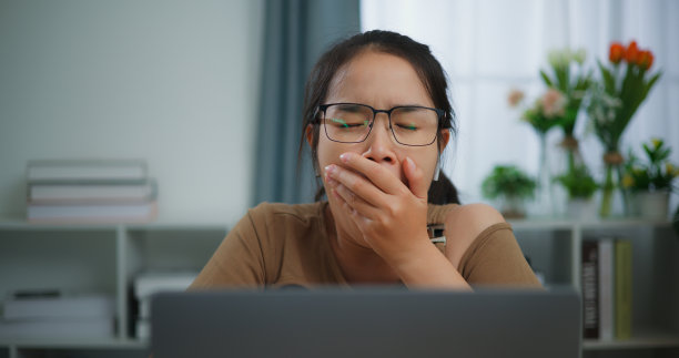 疲惫的年轻亚洲女人在桌子上用笔记本电脑工作图片下载