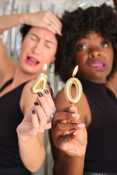 两位多种族女性参加40岁生日派对，点燃40根生日蜡烛图片下载
