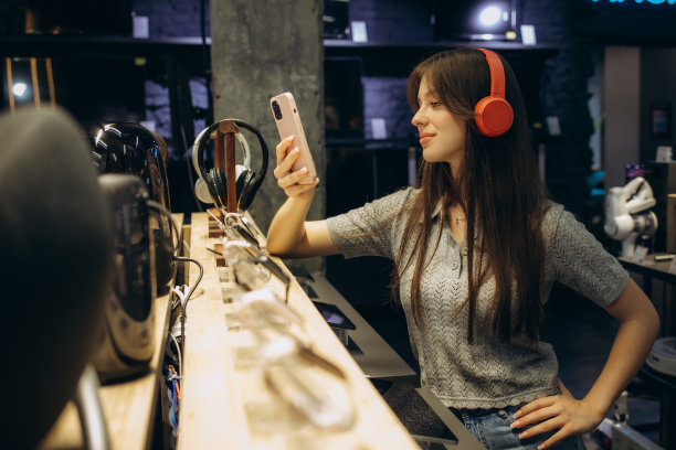 可爱时尚的快乐女孩在科技商店里测试和选择耳机的特写图片下载