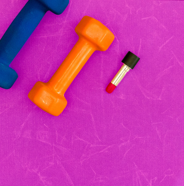 哑铃和口红在粉红色的背景与复制空间图片下载