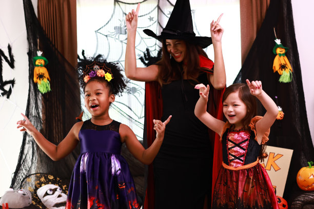 孩子们和年轻的妇女们在家里的万圣节派对上开心地跳舞。一群快乐的孩子穿着各种怪异的服装在装饰过的客厅里走来走去，跳着舞图片下载