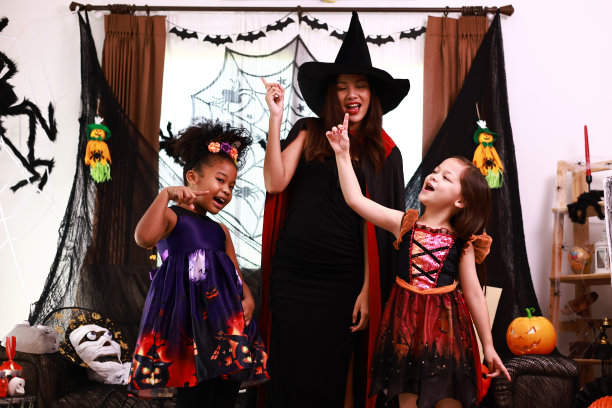 孩子们和年轻的妇女们在家里的万圣节派对上开心地跳舞。一群快乐的孩子穿着各种怪异的服装在装饰过的客厅里走来走去，跳着舞图片下载