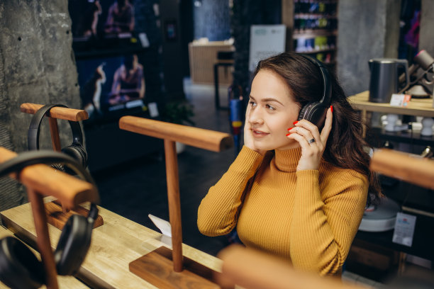 可爱时尚的快乐女孩在科技商店里测试和选择耳机的特写。图片下载