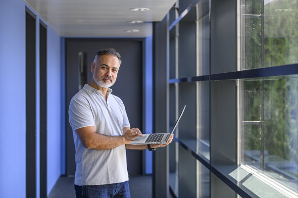 严肃的商人在走廊里用笔记本电脑工作图片下载