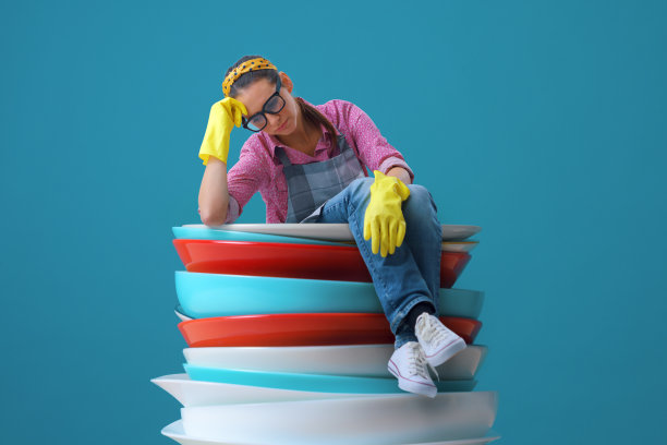 悲伤疲惫的家庭主妇坐在一大堆盘子上图片下载