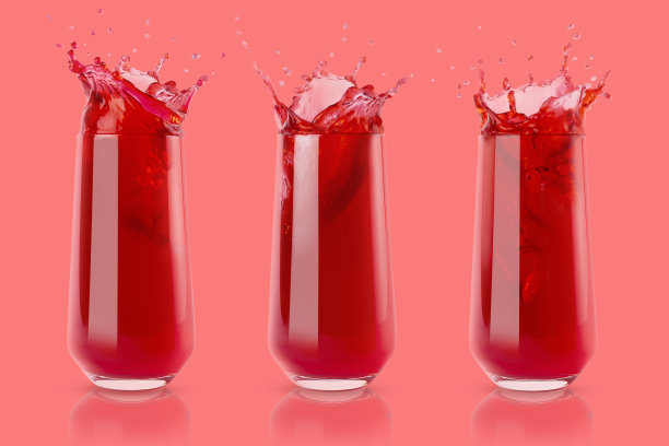一套三个浆果红色的新鲜果汁在玻璃反射，明亮的彩色飞溅，飞沫和漩涡在柔和的粉红色背景。夏日清爽甜素饮料。图片下载