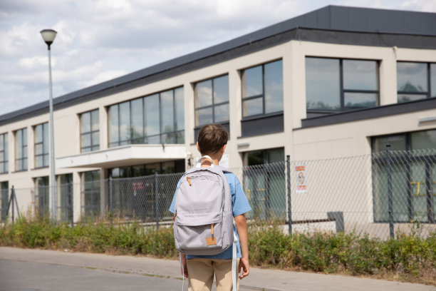 一个穿着蓝色t恤和浅色裤子的8岁男孩去上学。概念教育，返校，学年。后视图图片下载