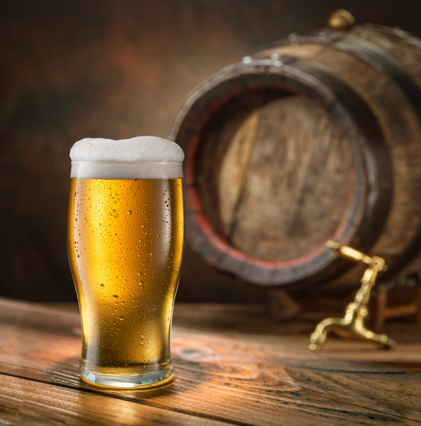 一杯冰啤酒和木质啤酒桶的背景。图片下载