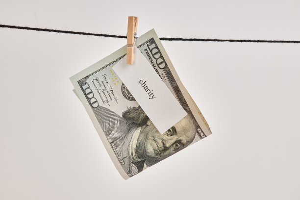 一张写着“慈善”字样的100美元钞票，用衣夹系在绳子上。图片下载