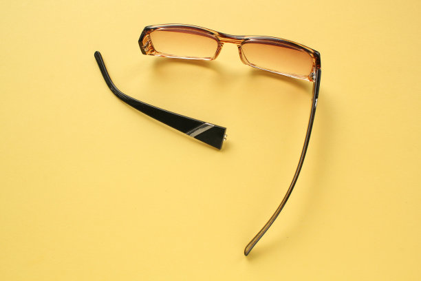 黄色背景上，旧的破损眼镜和破损的眼镜腿。视力不佳。重用和修复概念。健康的概念。光学眼镜失效。视力矫正眼镜破损。近距离，平躺图片下载
