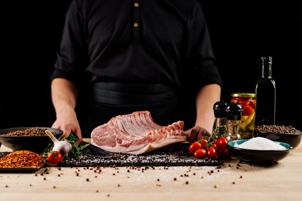 生排骨加香料，盐和迷迭香在深色木制背景。概念与男性厨师的手。图片下载