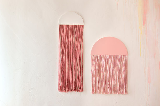 波希米亚风格的墙板，用棉线编织而成，用于家居装饰。温馨家居装饰概念。粉红色和红色的流苏在客厅与波西米亚室内设计在家里图片下载