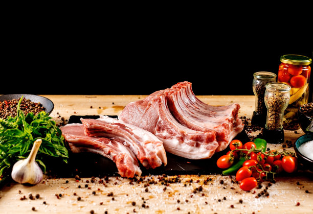 新鲜的、生的猪肉，用香料切成薄片，放在深色背景的木制肉板上图片下载