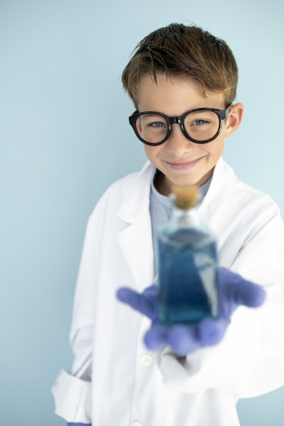 年轻的疯狂科学家穿着白大褂，戴着蓝手套，喝着蓝色的液体图片下载