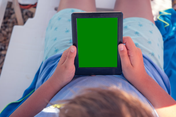 海边宁静:一个男孩和他的电子阅读器图片下载