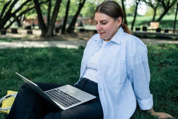 成功的职业女商人的肖像，穿着智能休闲，在城市公园的户外使用数字笔记本电脑。商务人士的概念。图片下载