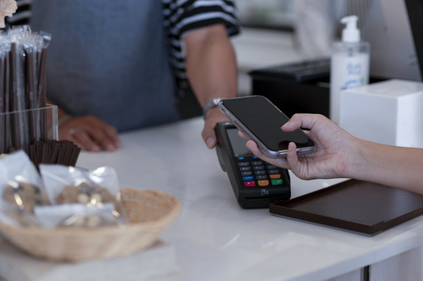 咖啡师在咖啡店接受信用卡支付，智能手机支付应用程序，在线支付。图片下载