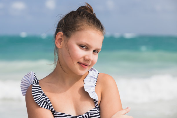 在海边拍的穿着泳装的漂亮小女孩的肖像。户外的照片图片下载